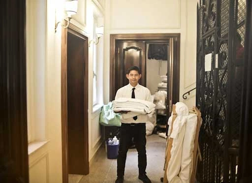Hotel staff holding clean linens in a tidy facility, highlighting efficient laundry operations to streamline processes and improve service quality.
