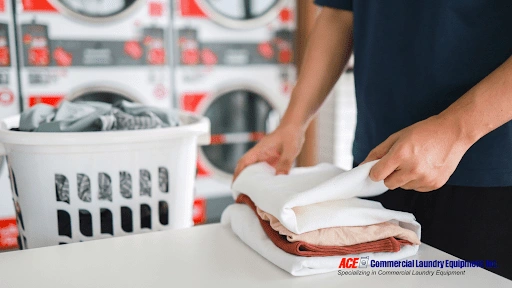 A person efficiently folding neatly stacked, freshly washed laundry, showcasing practical time-saving laundry techniques.