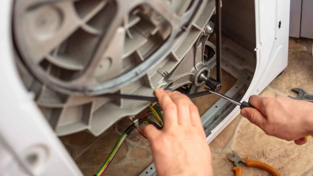 Technician repairing the internal components of a commercial washing machine motor.