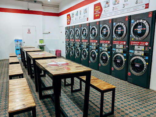 Interior of a modern self-service laundromat with multiple front-load washers and seating, highlighting organized and efficient laundry operations.