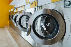 Row of commercial washing machines in a communal laundry area, representing modern, efficient equipment essential for resident satisfaction.